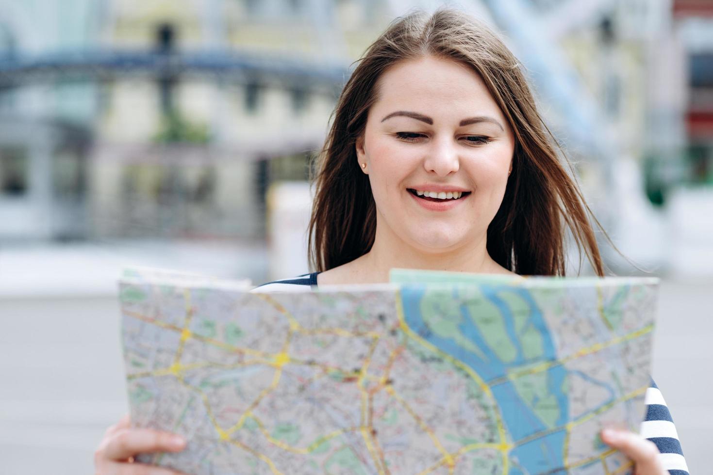 una mujer con un mapa en sus manos camina por las calles de la ciudad, buscando el camino correcto foto