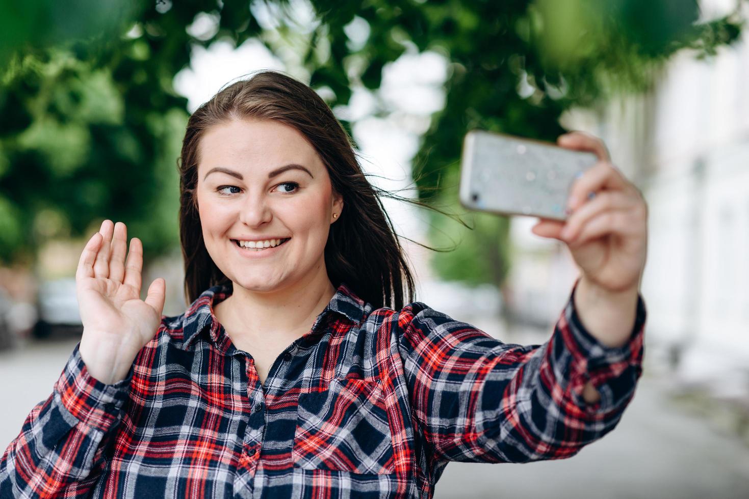 mujer joven feliz en el fondo de la ciudad haciendo selfie por cámara. foto