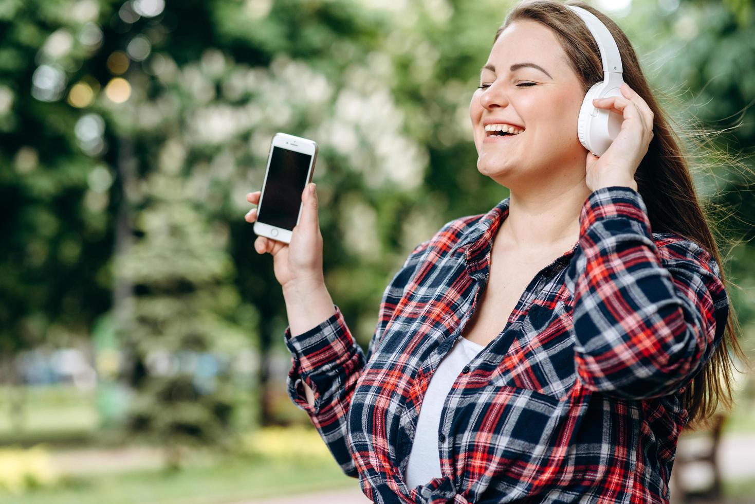 hermosa y atractiva morena disfruta de una canción favorita que sale de los auriculares. foto