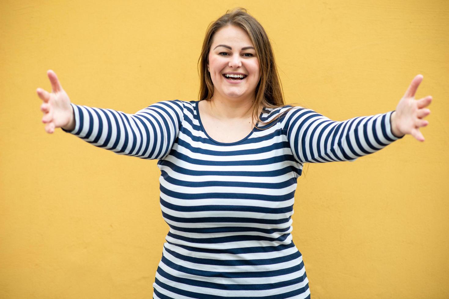 Smiling, cute woman with open arms on orange background photo