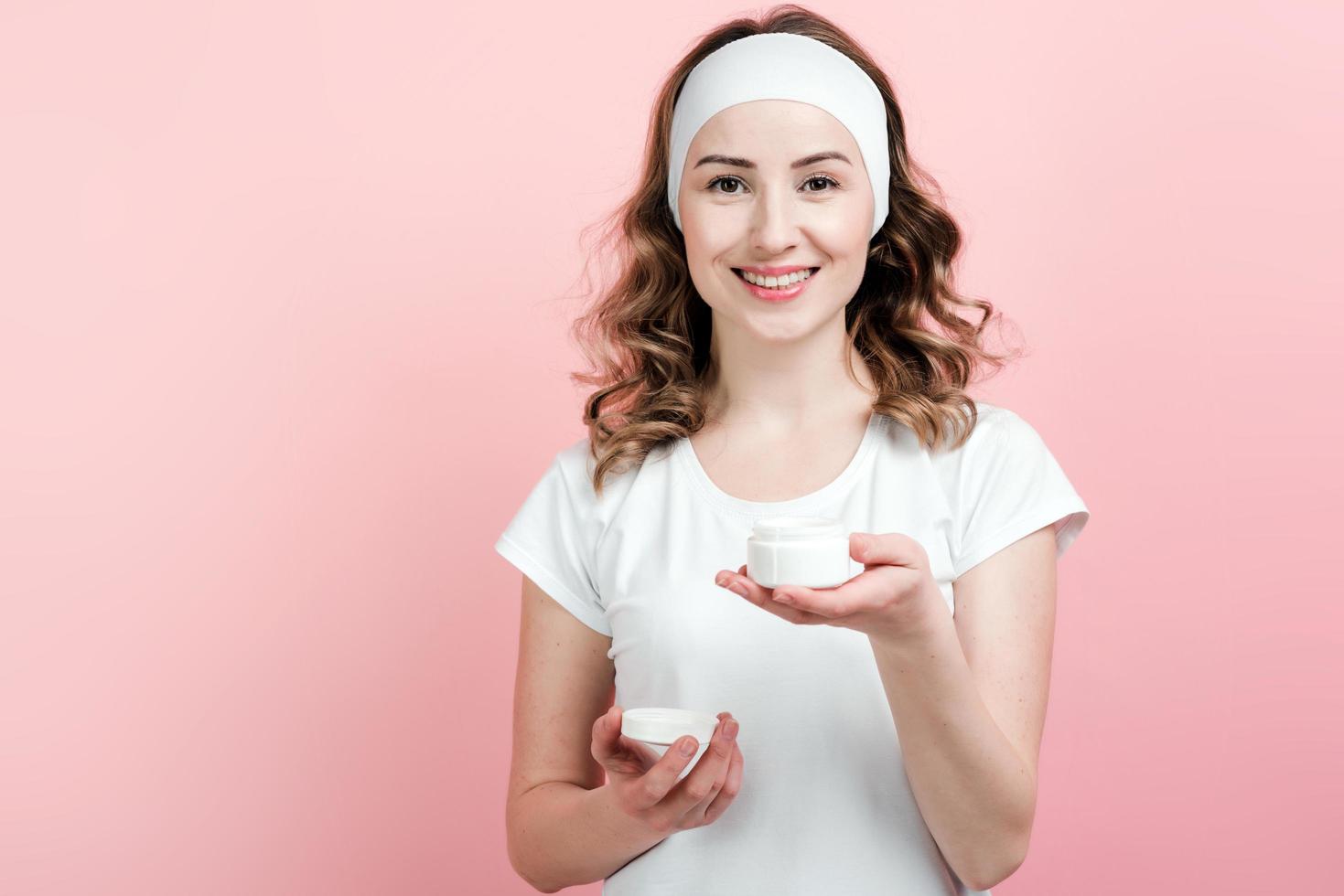 Happy girl with a bandage on her head holds in hand a jar of moisturizer photo