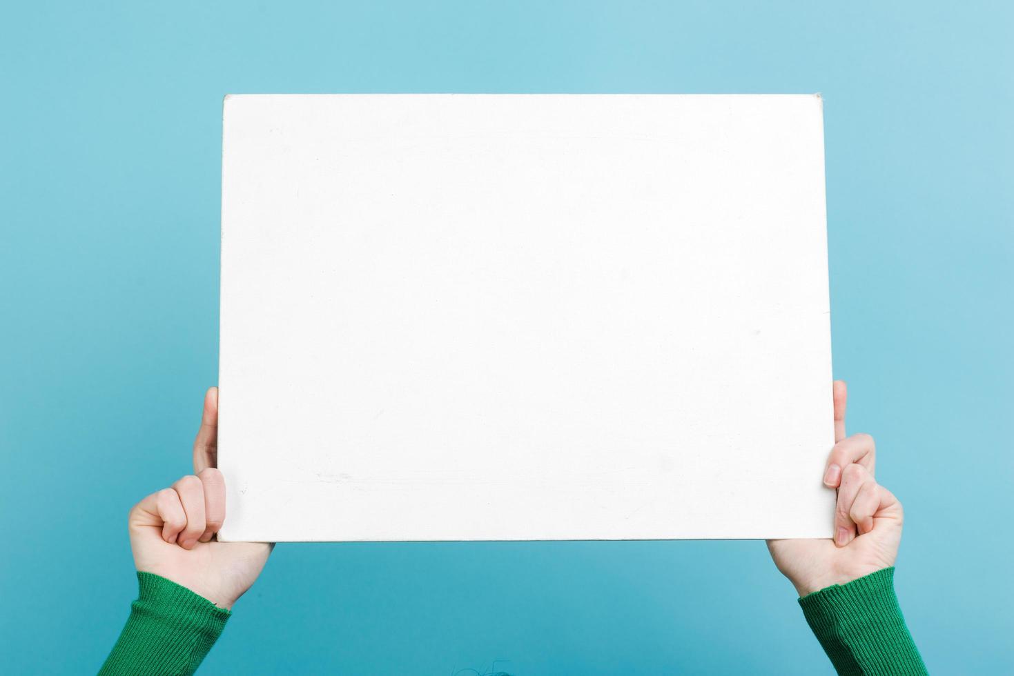 Woman's Hands holding empty white blank board isolated on blue background photo