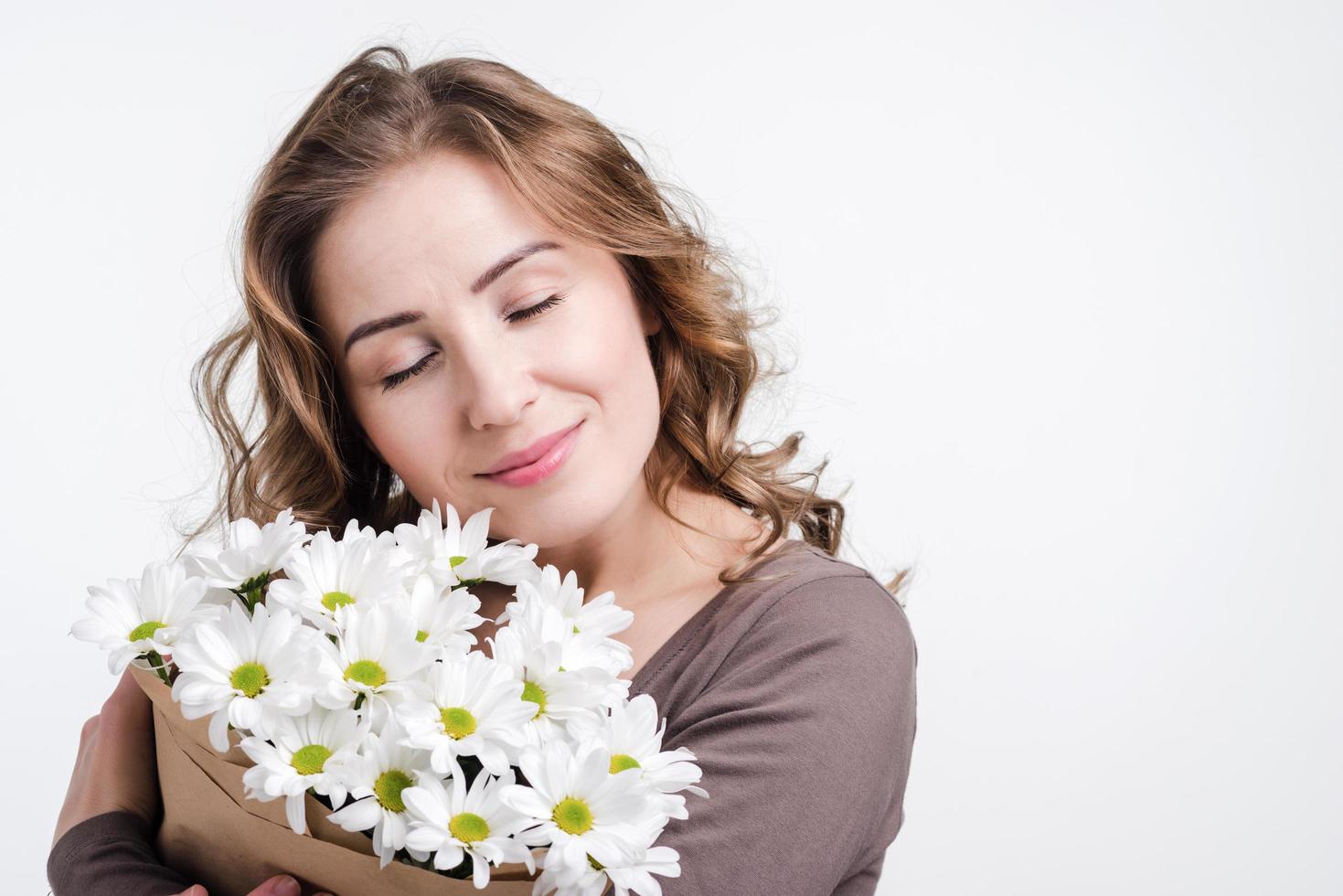 Girl holding flowers in studio on white wall background photo