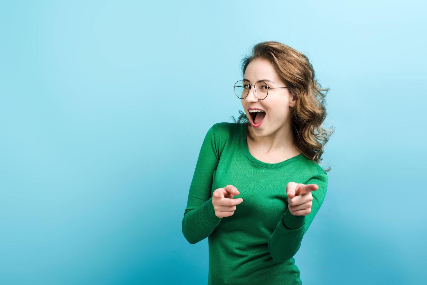 chica alegre abriendo la boca señala con el dedo a la cámara, de cerca. foto