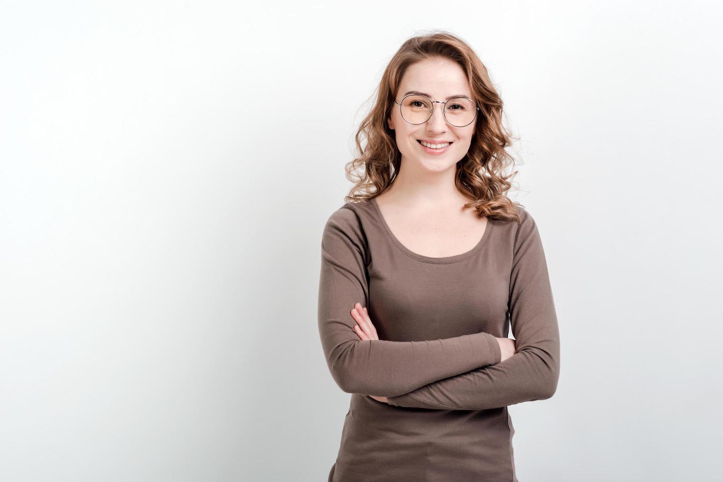 Smiling girl in glasses stands with arms crossed.Isolated on white background. photo