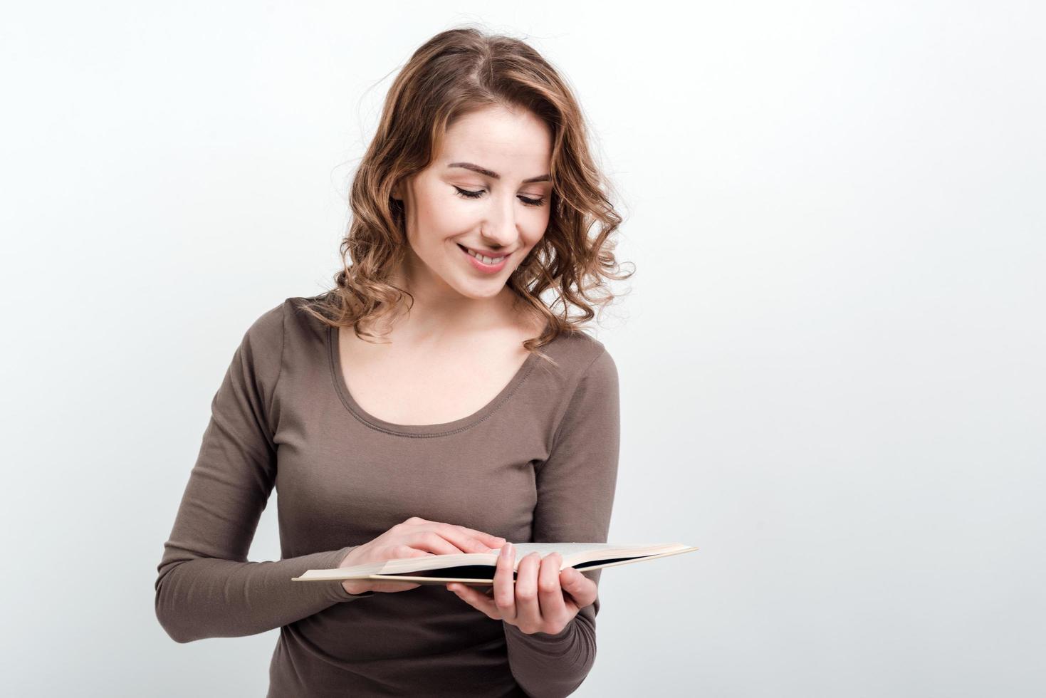 Smiling girl standing reads a book isolated on a white background. photo