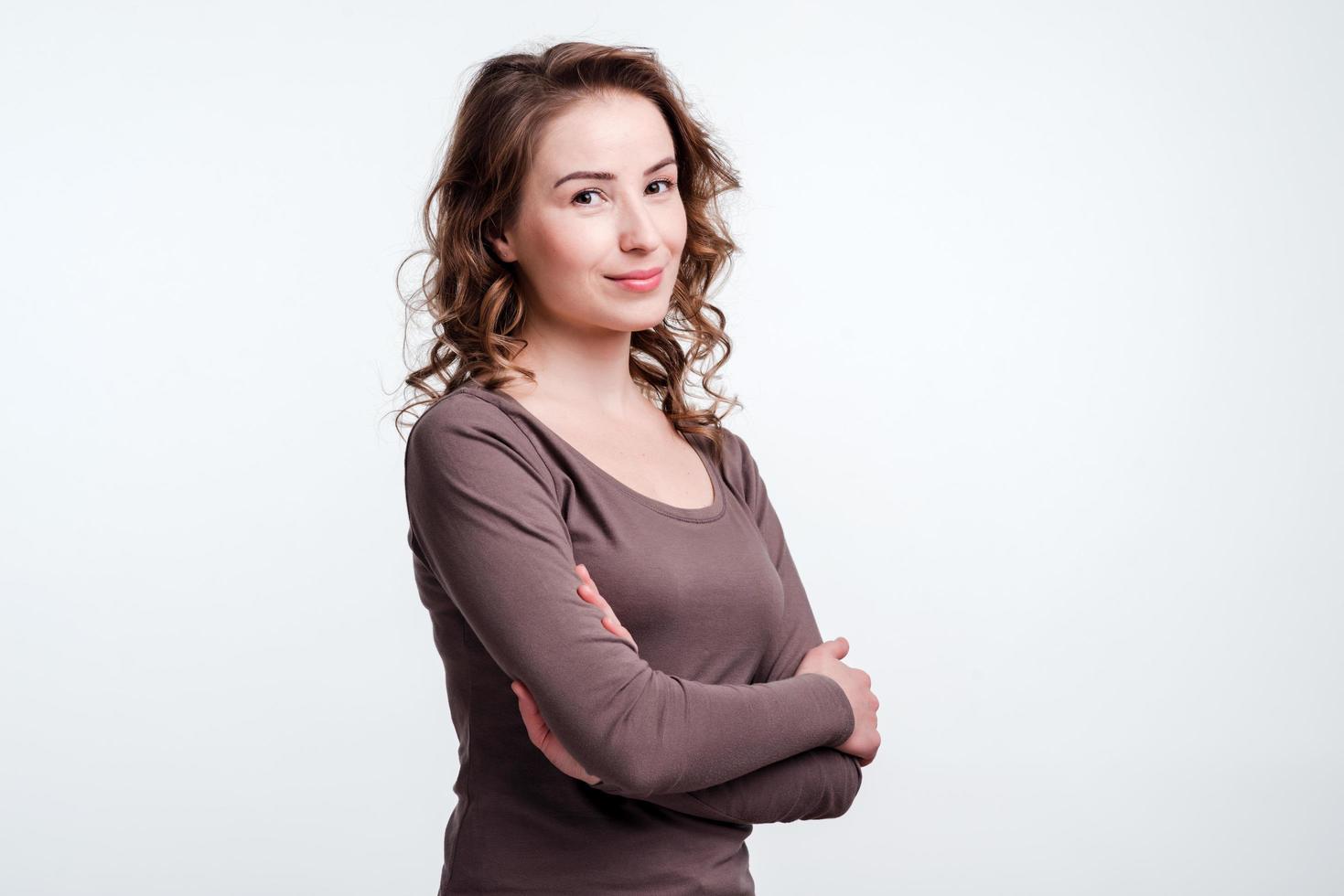 Attractive, young girl crossed her arms and holding them under her chest. Smiling woman looking in front of camera. photo