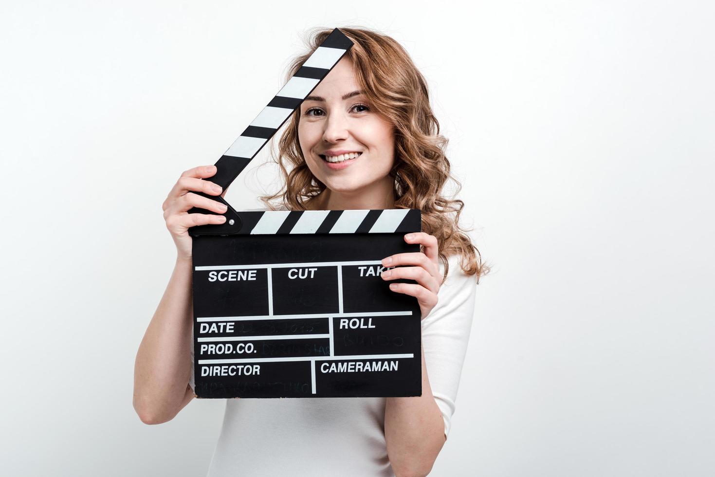 Chica guapa con un tablero de película sobre un fondo blanco. foto