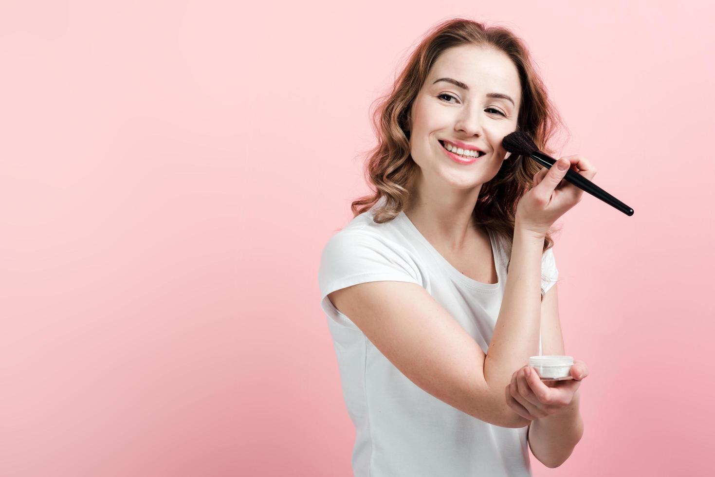 Smiling beautiful girl in white t-shirt powder face, on pink background. photo
