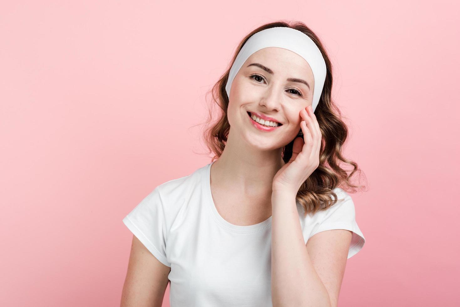 niña sonriente posando con diadema. aislado sobre fondo rosa. foto