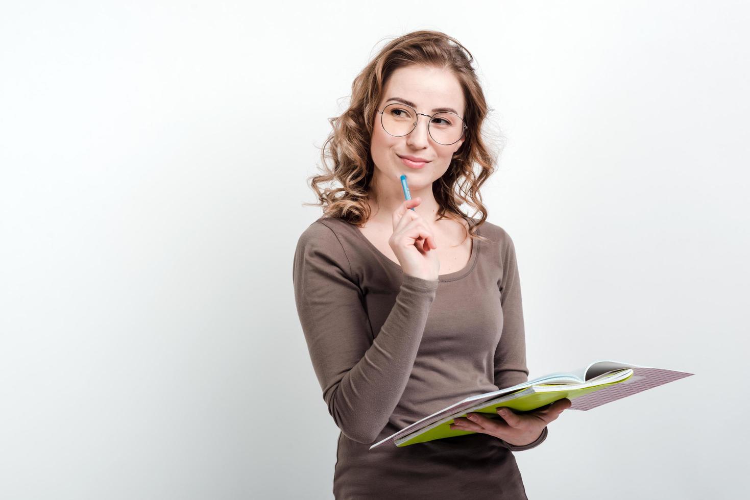 Young girl thinking holding a book and pen. photo