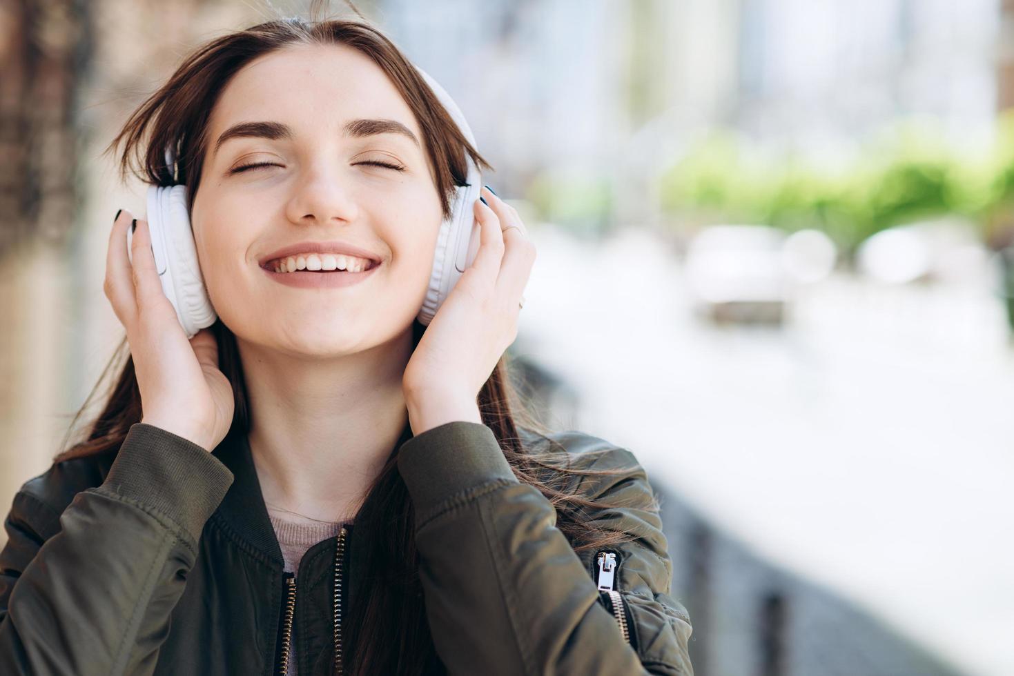 Happy, young girl enjoys the music coming from the headphones. photo