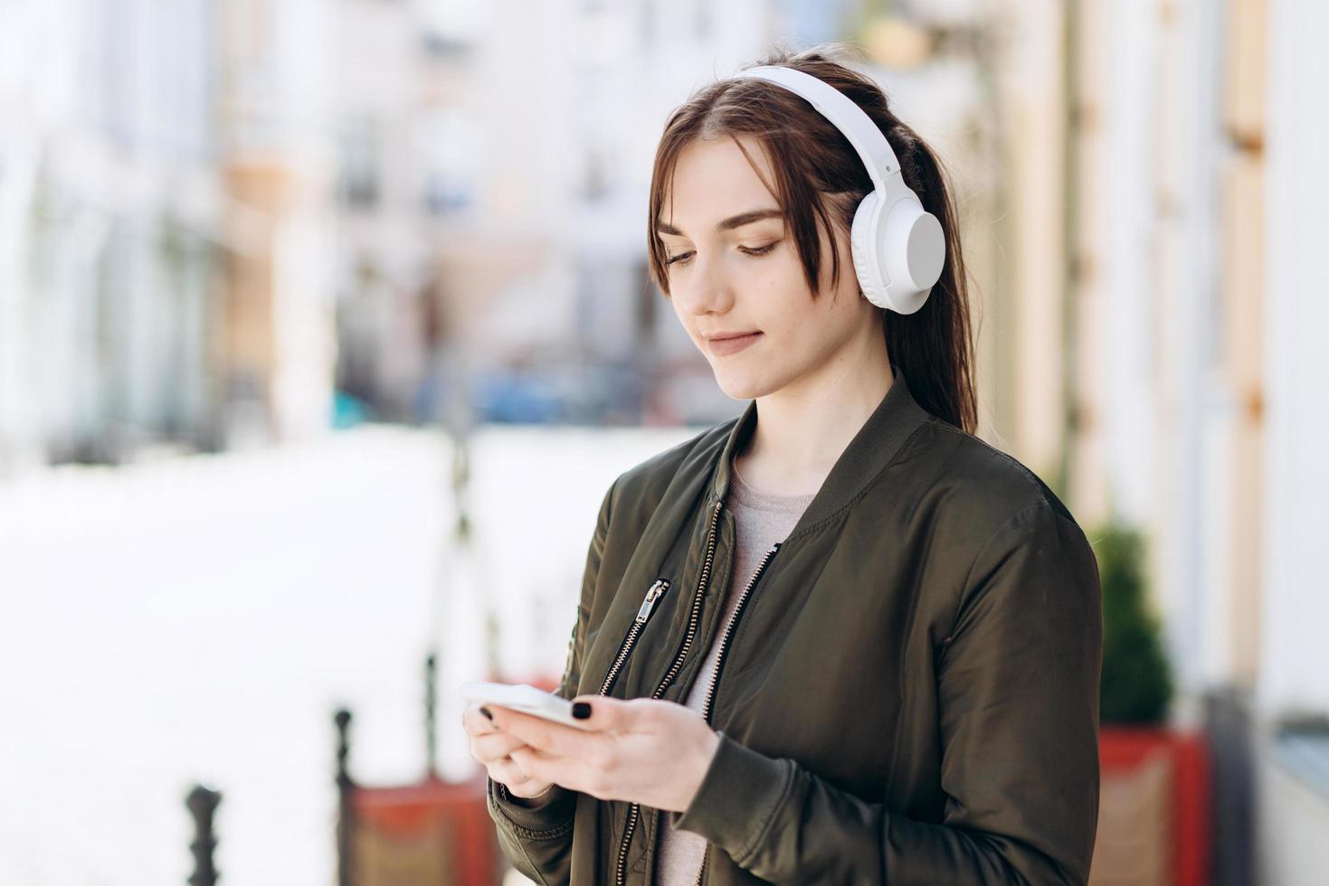 Close-up portrait of nice attractive cute adorable cheerful girl in headphones looking at something on the phone photo