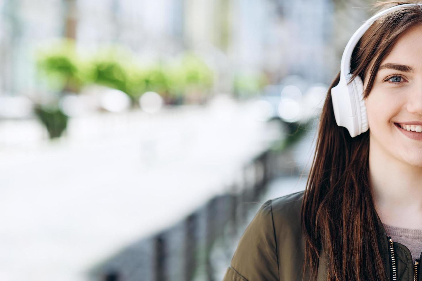 Young woman wearing headphones with a happy face standing in middle of street photo