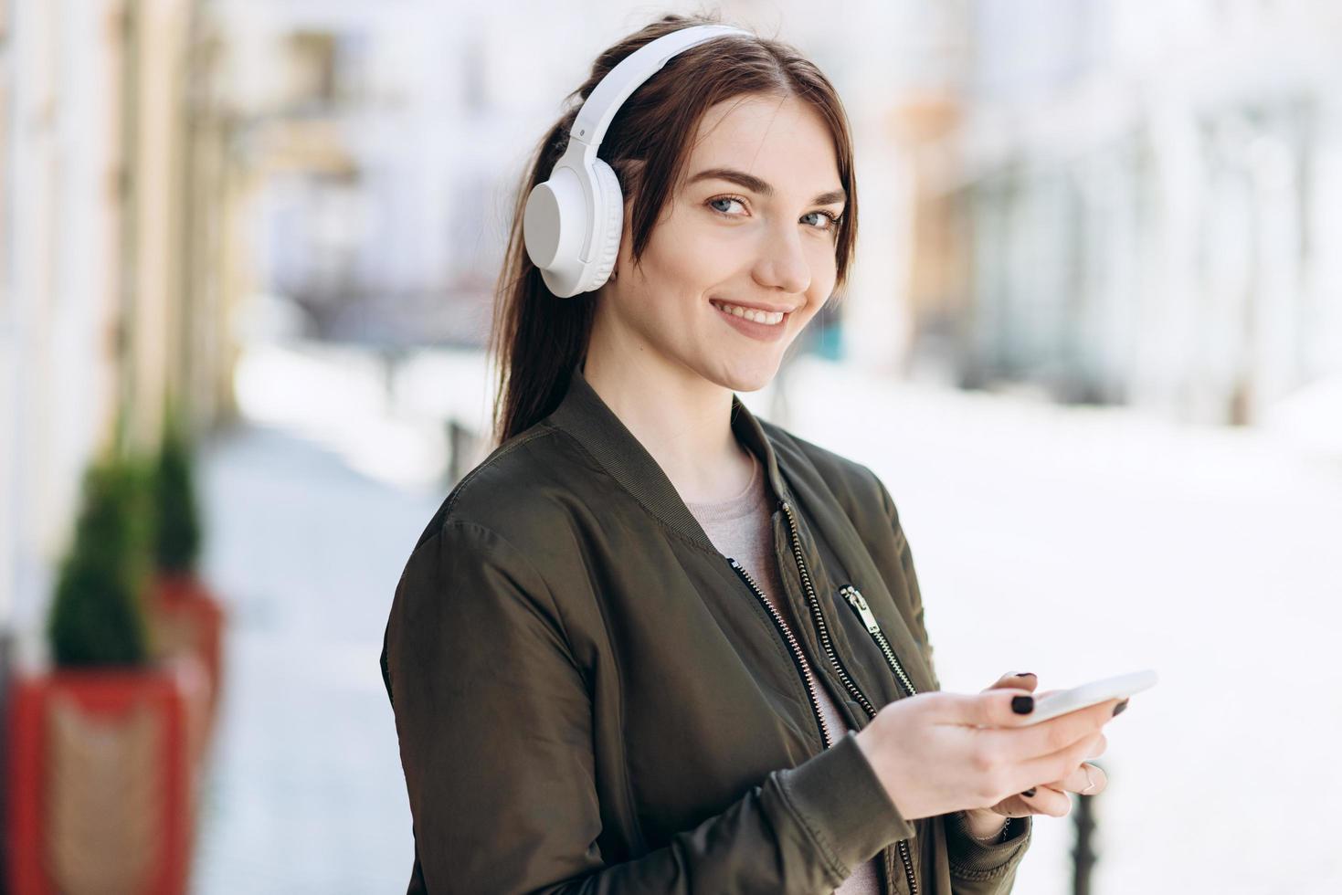 chica joven en un collar y un teléfono en sus manos, mirando a la cámara. foto