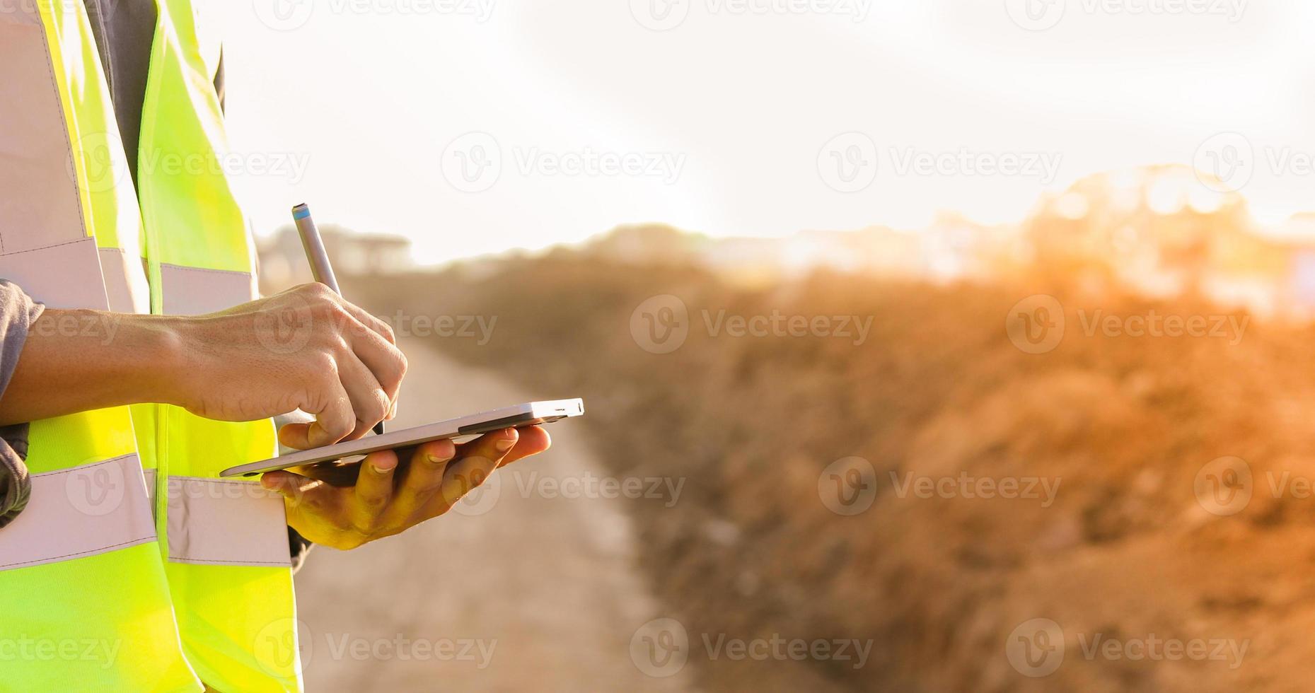 Asian engineer with hardhat using  tablet pc computer inspecting and working at construction site photo