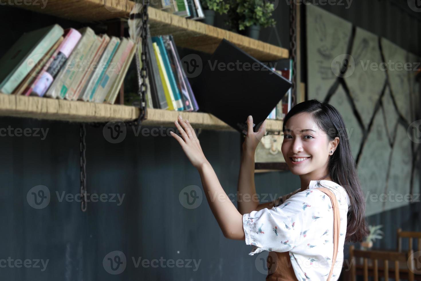 estudiantes asiáticas sosteniendo la sección en el estante de libros foto