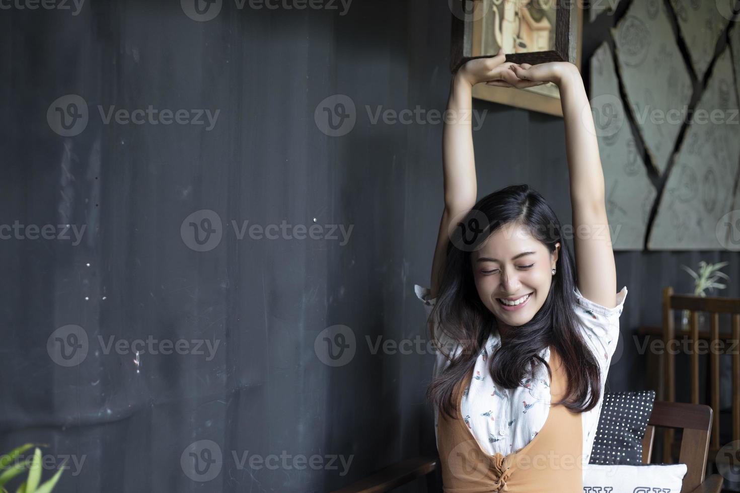 Mujer asiática estirando y sonriendo en la oficina en casa foto