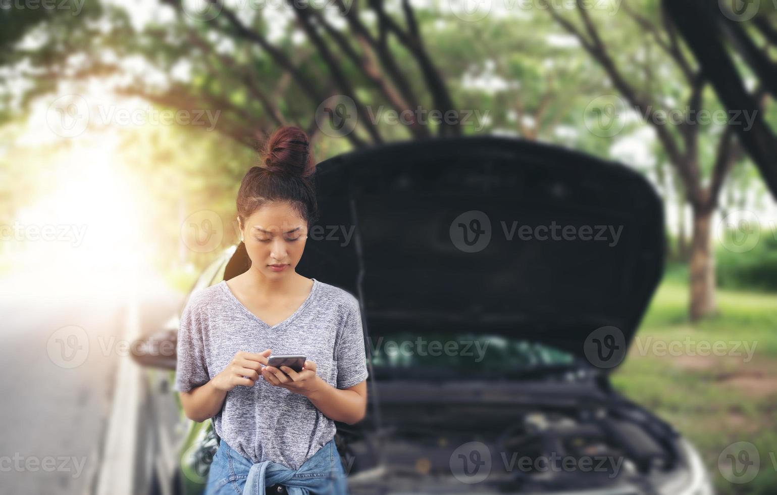 Mujer asiática con teléfono móvil mientras mira y estresado hombre sentado después de una avería de coche en la calle foto