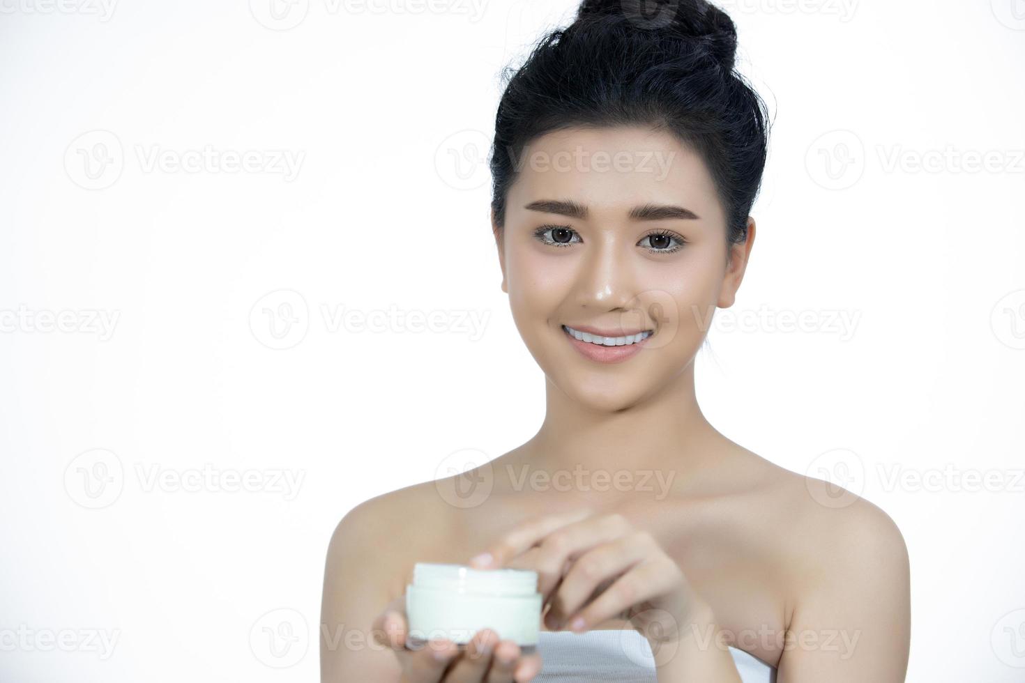 A beautiful woman asian using a skin care product, moisturizer or lotion taking care of her dry complexion. Moisturizing cream in female hands . photo