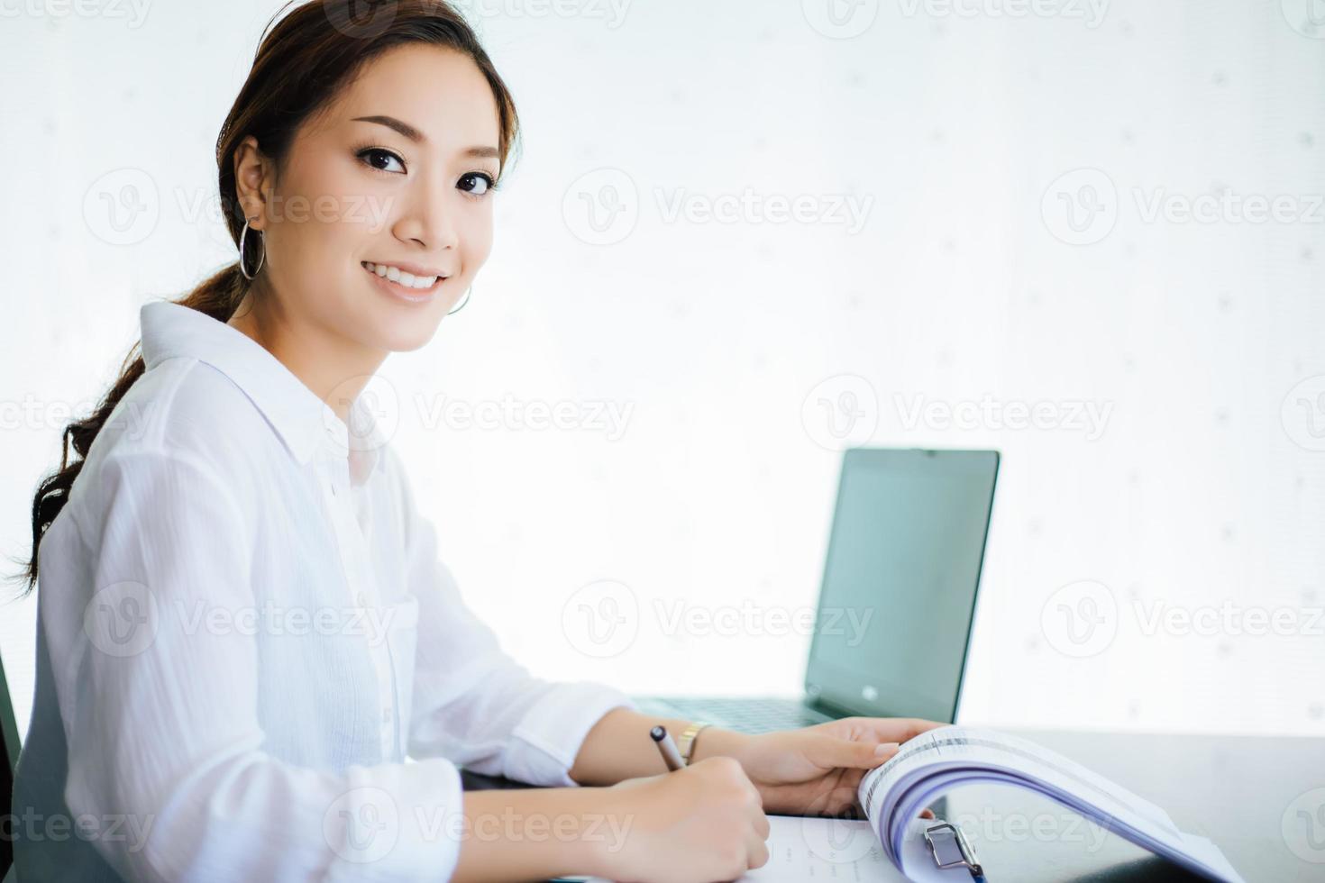 Mujeres de negocios asiáticas que usan el cuaderno y sonríen felices por trabajar foto