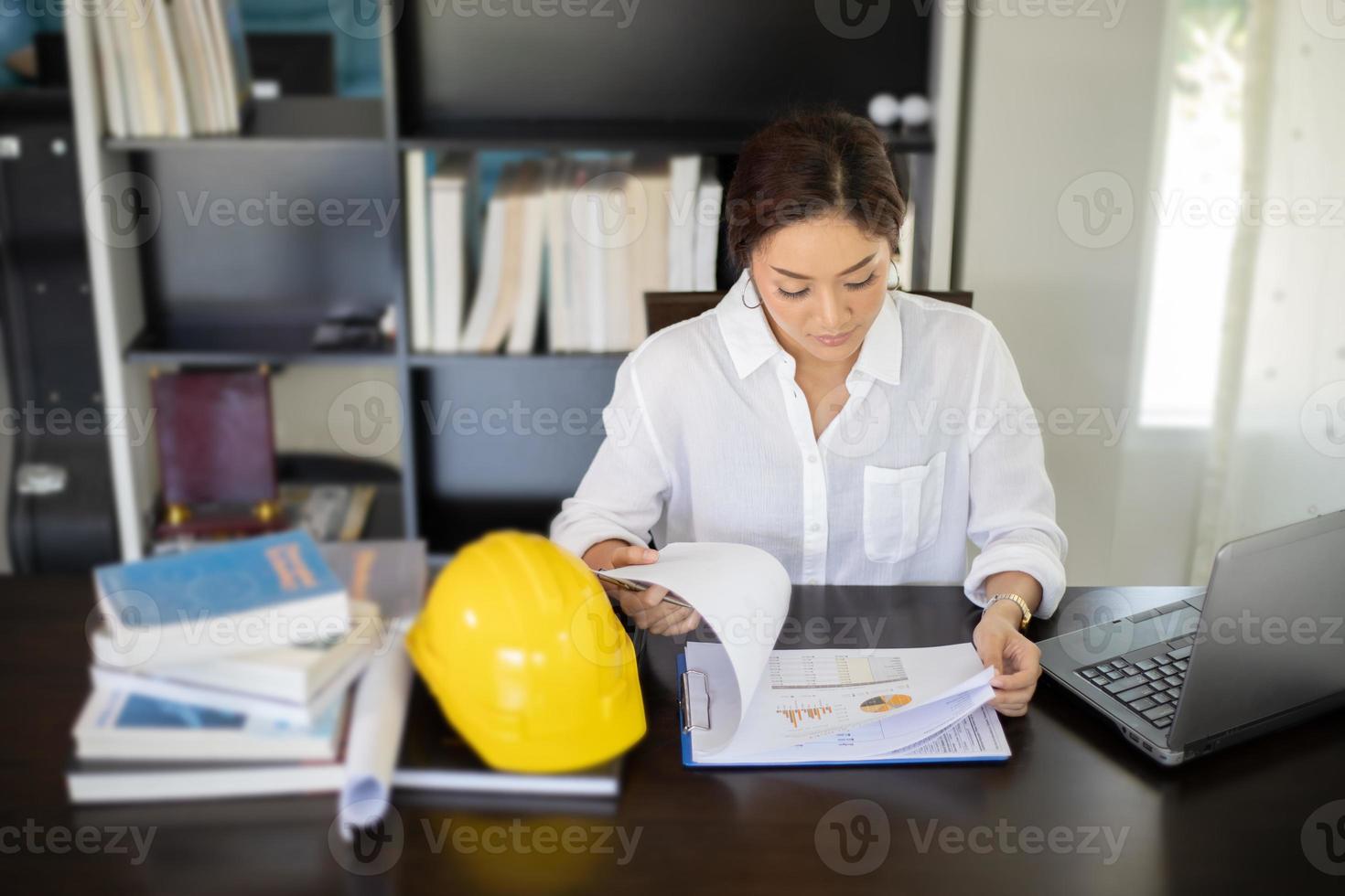 Asian women engineering inspecting and working and holding blueprints at office photo