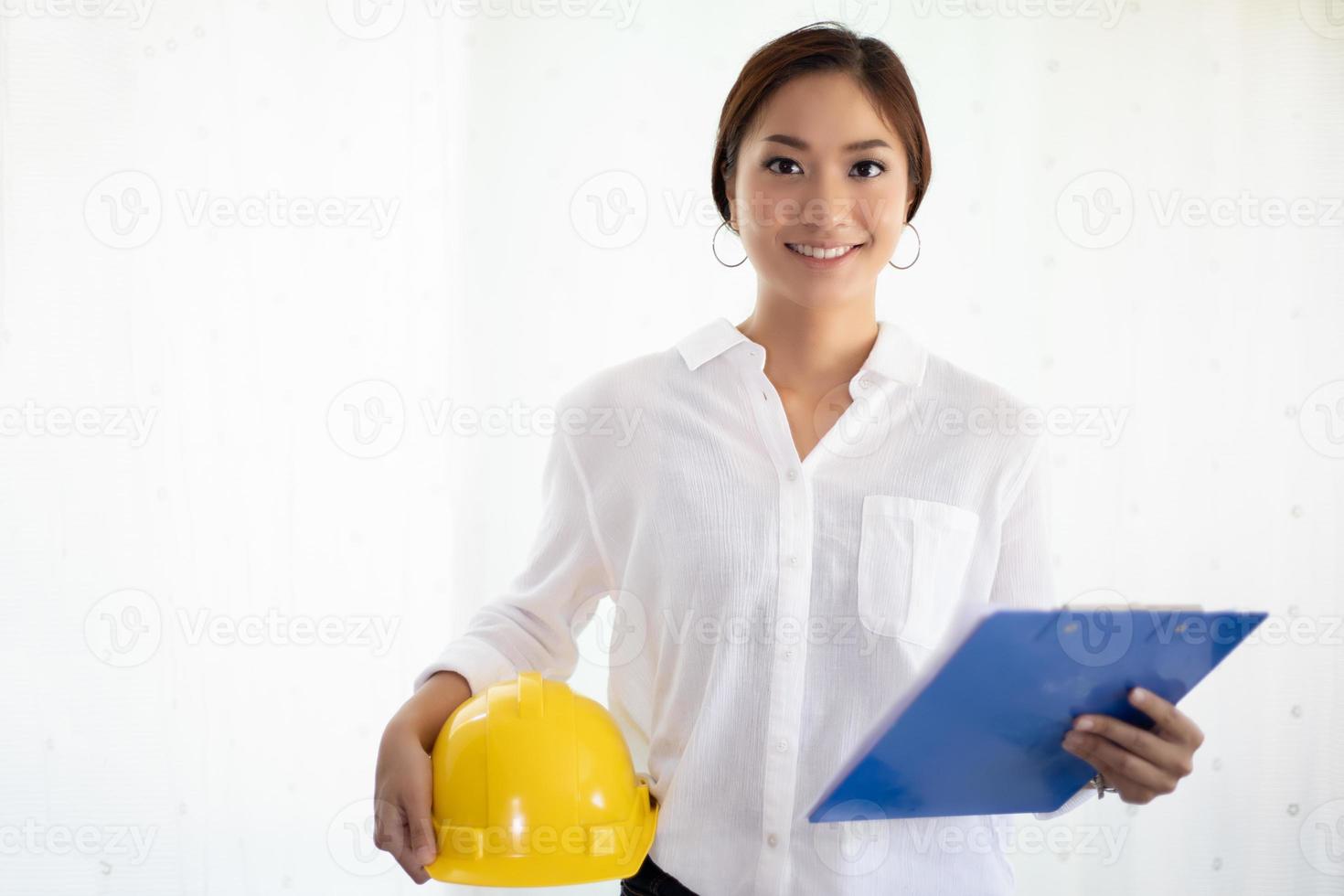 Mujeres asiáticas de ingeniería inspeccionando y trabajando y sosteniendo planos en la oficina foto