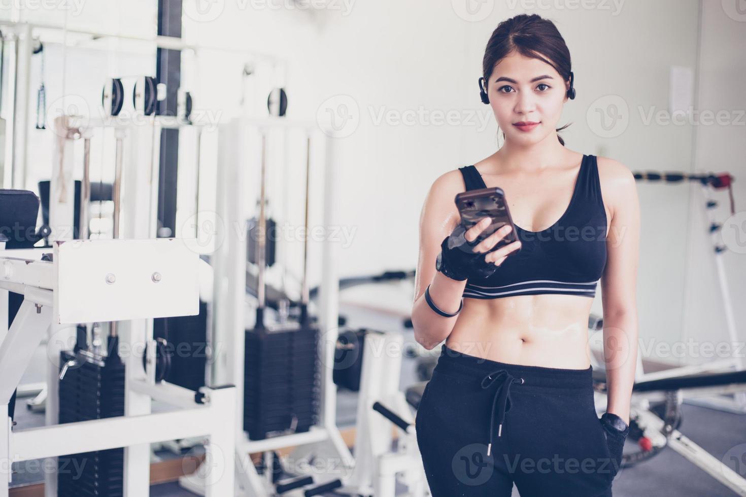 atleta asiático en ropa de moda de ropa deportiva. deportista escuchando música usando la aplicación de teléfono para el rastreador de actividad física: monitor de frecuencia cardíaca que rastrea su progreso de salud en el teléfono inteligente. foto