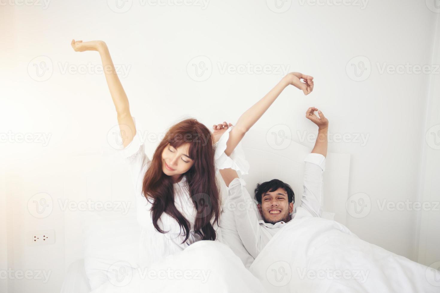 Amante de las parejas que se despierta en su cama completamente descansada y abre las cortinas por la mañana para que entre aire fresco. foto