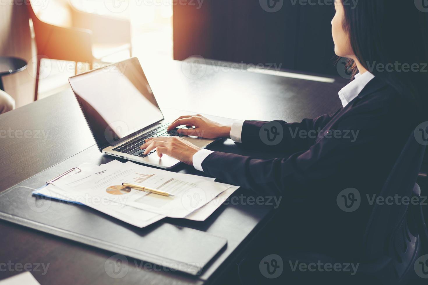 Asian businesswomen using laptop computer  analysis documents and graph financial diagram on office table working photo