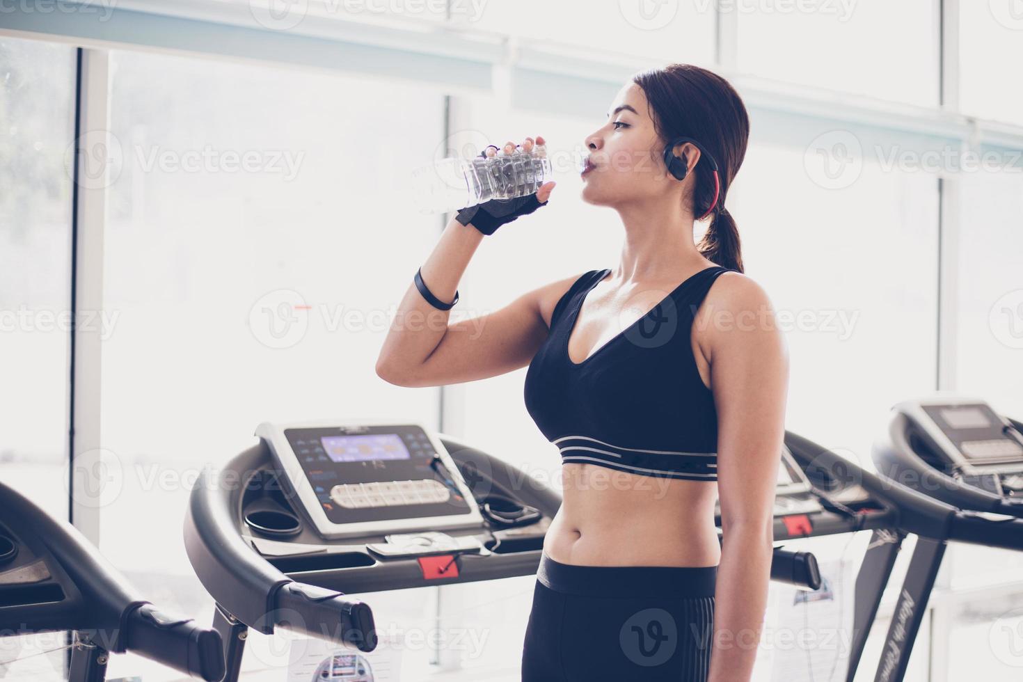 Sporty woman asia drinking water after exercises in the gym. Fitness - concept of healthy photo