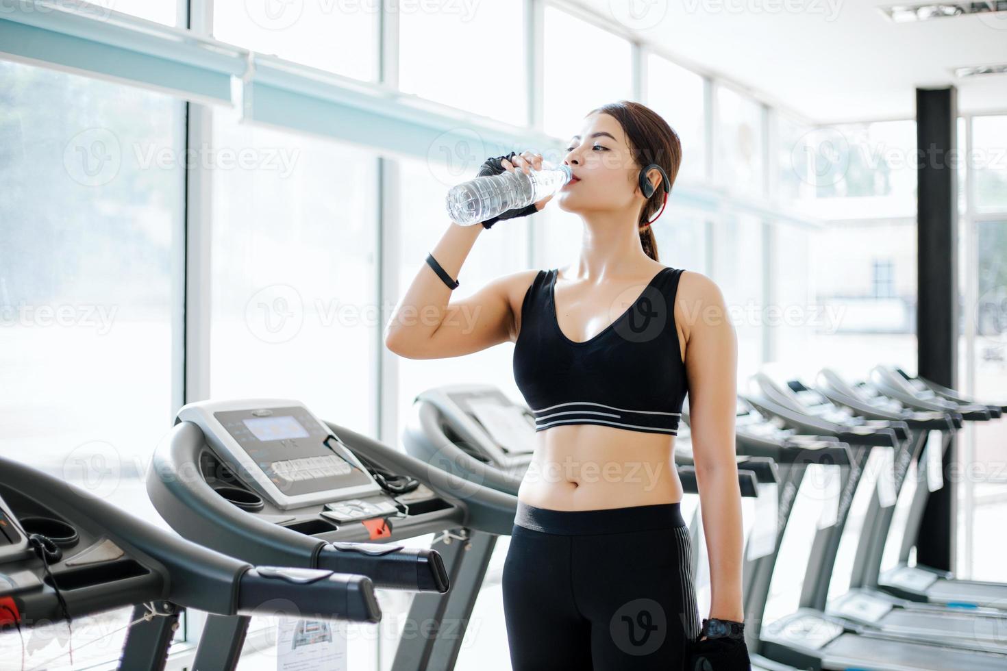 mujer deportiva asia agua potable después de ejercicios en el gimnasio. fitness - concepto de salud foto