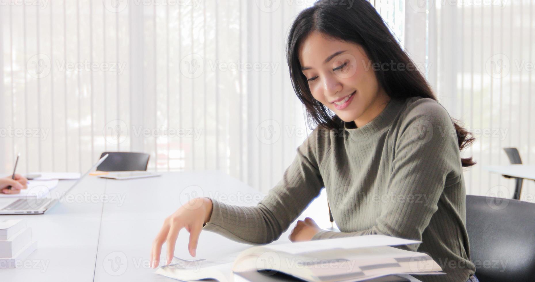 Las estudiantes asiáticas sonríen y leen un libro y usan el cuaderno para ayudar a compartir ideas en el trabajo y el proyecto. y también revisar el libro antes del examen foto