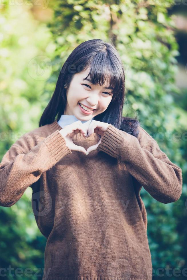 Beautiful young asian women making heart shape with hands and Smiling happy in love outdoors photo