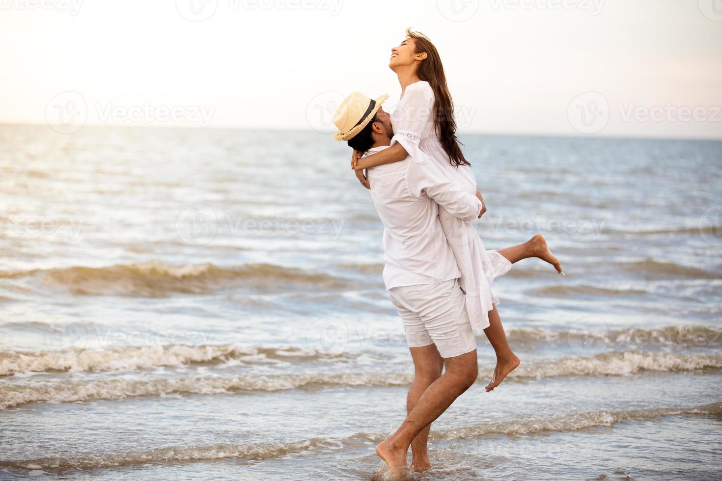 Feliz pareja romántica amante tomados de la mano juntos caminando por la playa foto