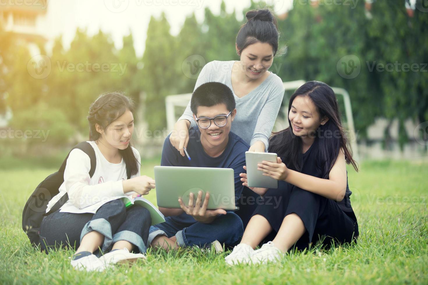 Grupo asiático de estudiantes compartiendo ideas para trabajar en el jardín del césped del campus. foto