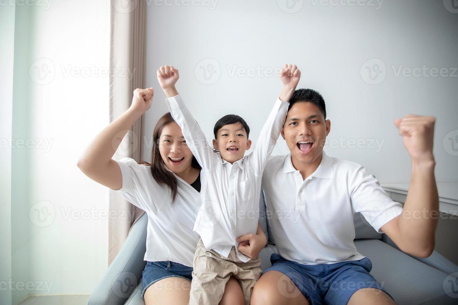 Familia emocionada y feliz con los brazos levantados mientras ve la televisión en casa foto