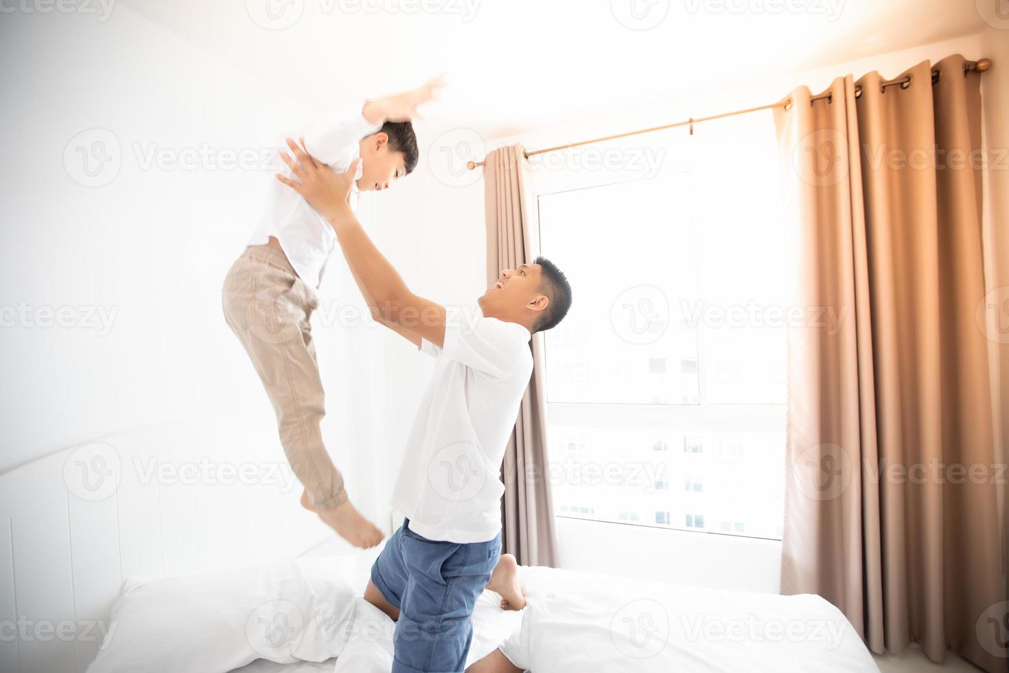 Feliz familia asiática con su hijo en casa en el dormitorio jugando y riendo foto