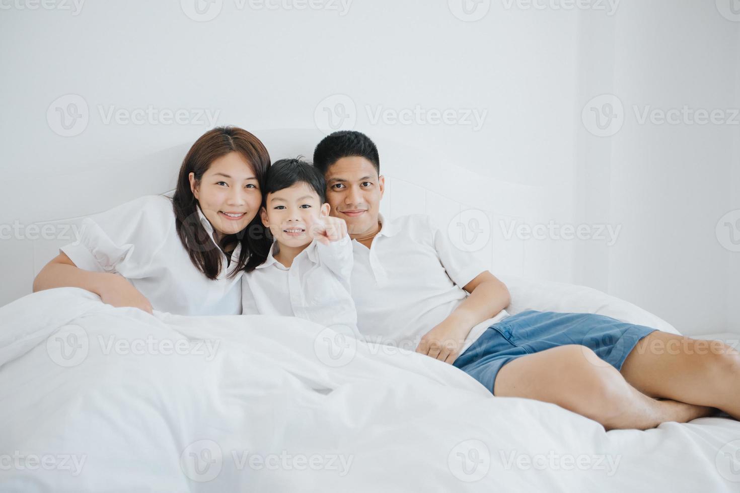 Feliz familia asiática con su hijo en casa en el dormitorio jugando y riendo foto