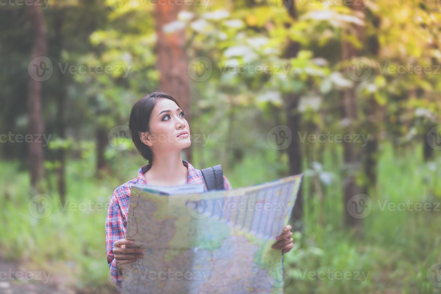 Las mujeres jóvenes excursionistas mirando el mapa y relajarse en el concepto de vacaciones viajan en el bosque foto