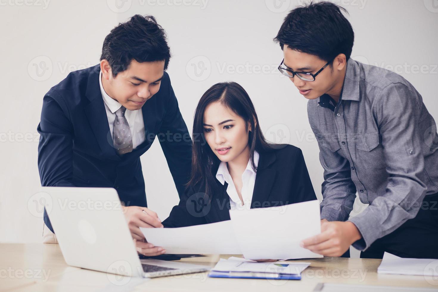Hombres de negocios asiáticos y grupo que usan el cuaderno para socios comerciales que discuten documentos e ideas en reuniones y mujeres de negocios sonriendo felices por trabajar foto