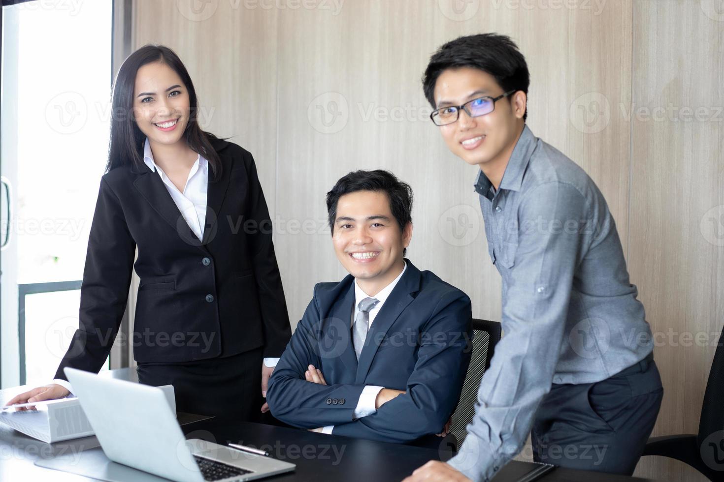 Hombres de negocios asiáticos y grupo que usan el cuaderno para socios comerciales que discuten documentos e ideas en reuniones y mujeres de negocios sonriendo felices por trabajar foto