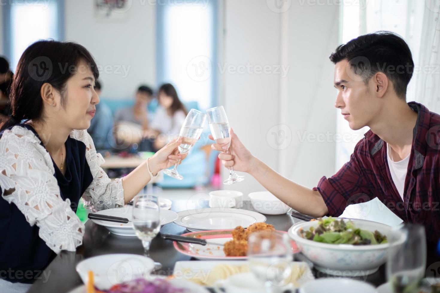 Asian young couple enjoying a romantic dinner  evening drinks while sitting at the dinning table on the kitchen together,soft focus photo