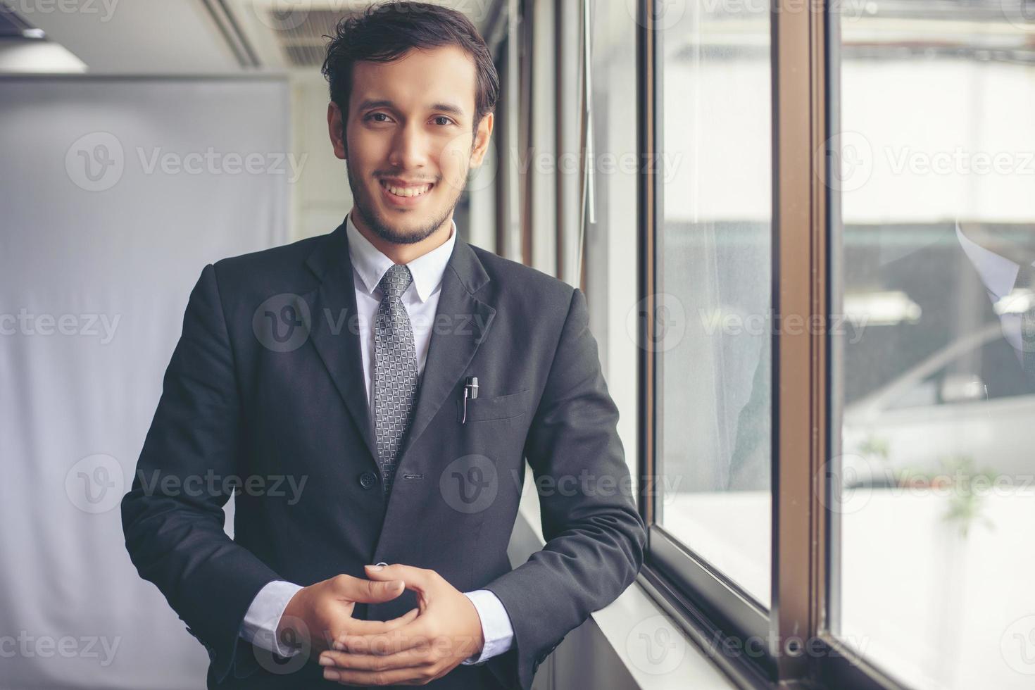 Happy handsome businessman standing and smiling in office photo