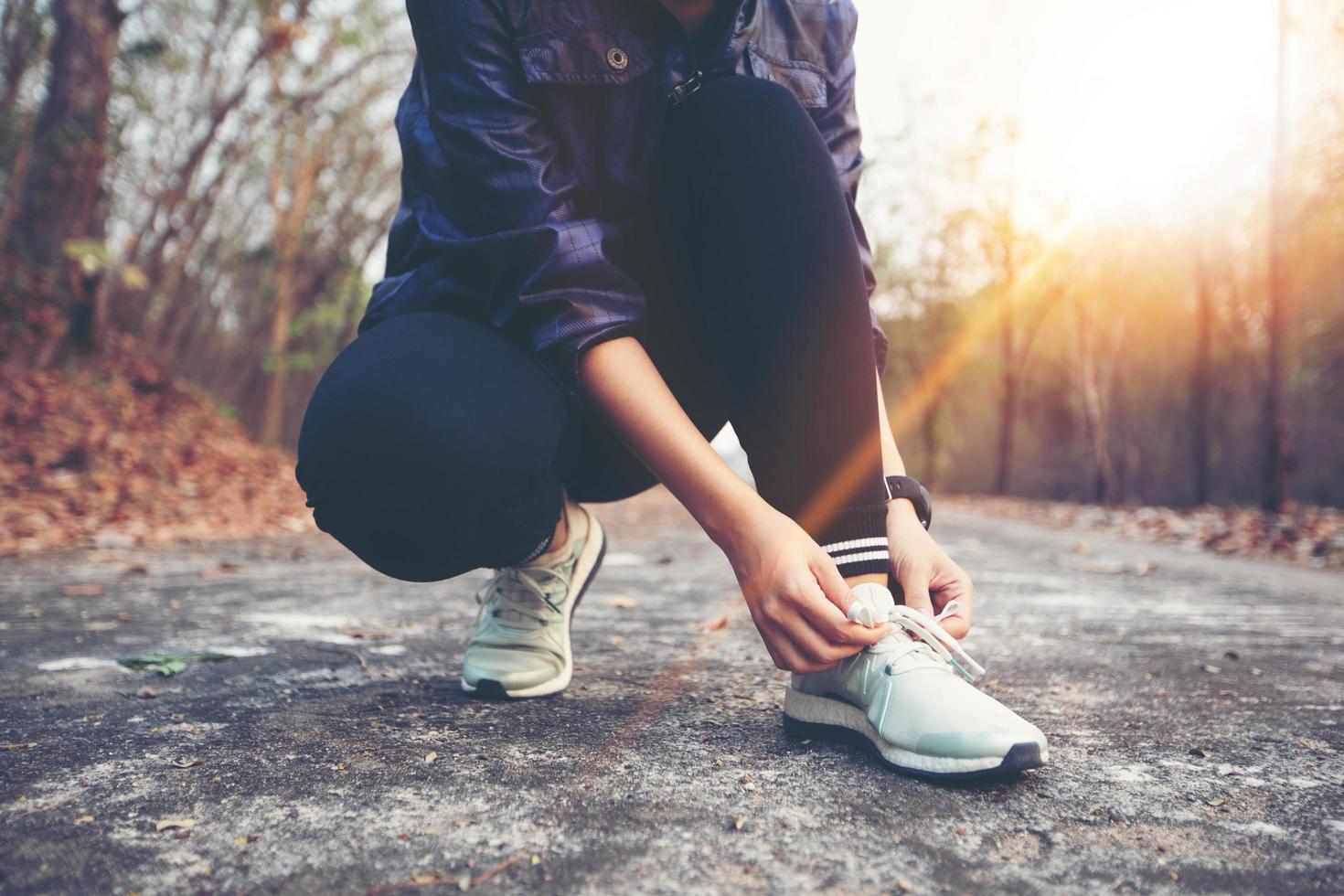 Mujer atar cordones de zapatos para corredor de fitness deportivo preparándose para trotar al aire libre en el sendero del bosque a fines del verano o en el otoño. foto