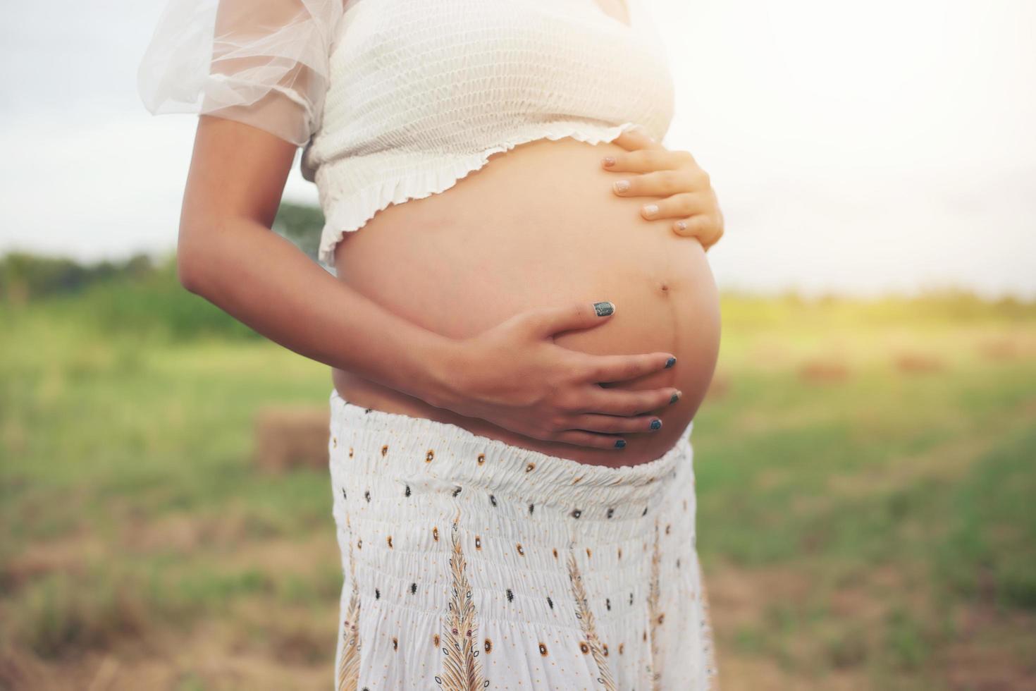 Feliz y orgullosa mujer asiática embarazada mirando su vientre foto