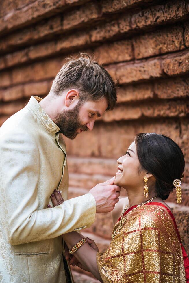 La novia asiática y el novio caucásico tienen tiempo romántico con el vestido de Tailandia foto