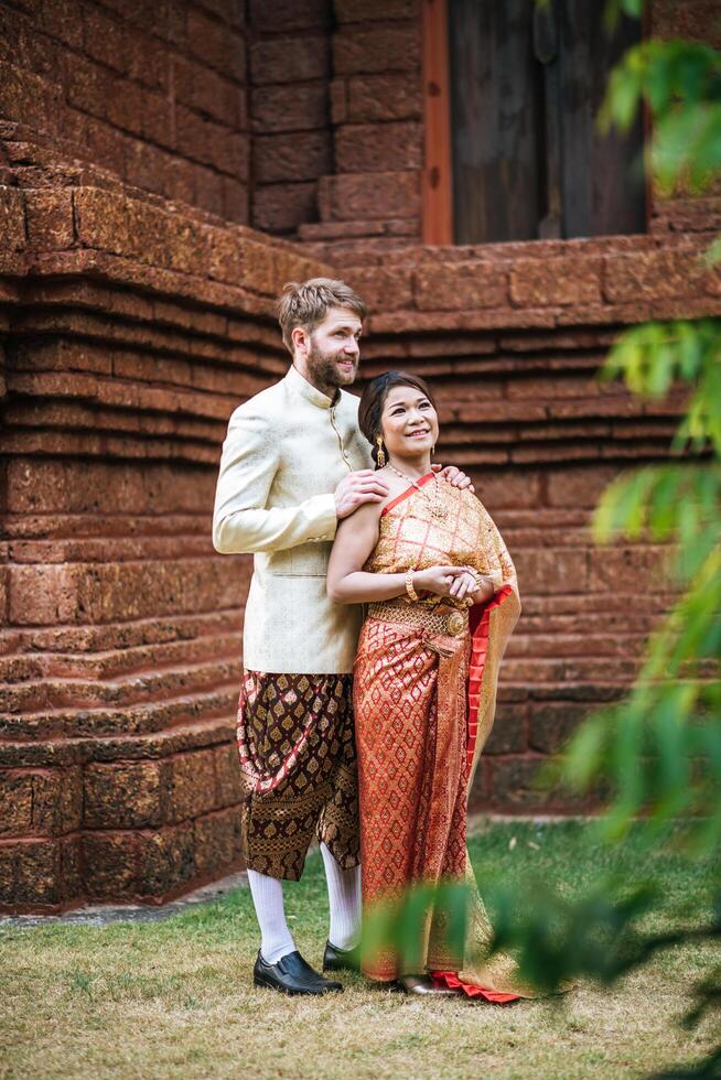 La novia asiática y el novio caucásico tienen tiempo romántico con el vestido de Tailandia foto