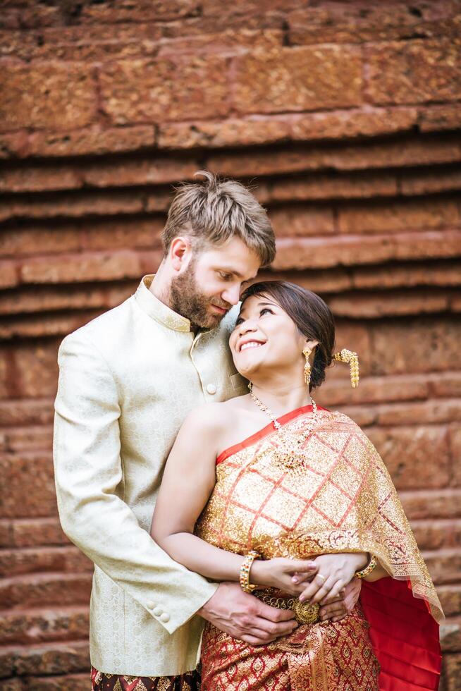 La novia asiática y el novio caucásico tienen tiempo romántico con el vestido de Tailandia foto