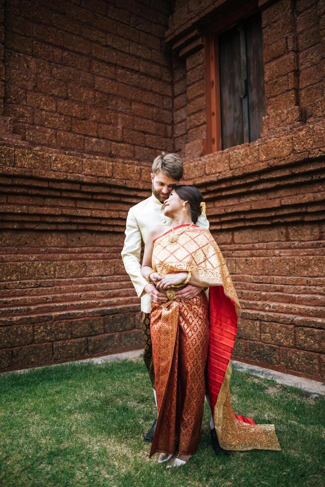 La novia asiática y el novio caucásico tienen tiempo romántico con el vestido de Tailandia foto